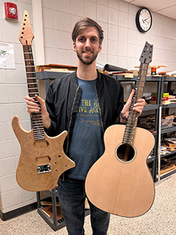 Student Lucas Randall holds two guitars he built in 2023