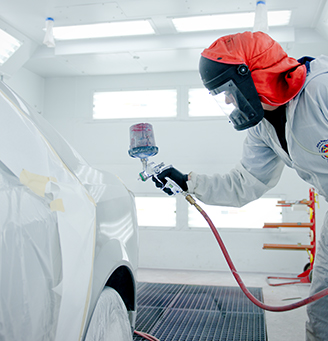 Tech spraying vehicle in paint booth