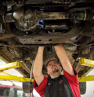 Tech working under the body of a car on a lift