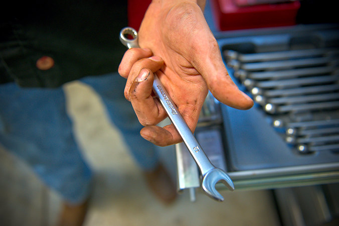 A hand hoding a wrench out to the cammera