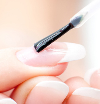 Nail brush applying clear polish to a nail (closeup)