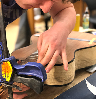 Student working on a guitar fretboard