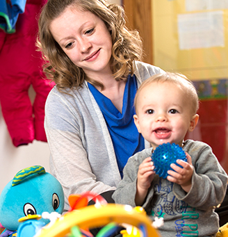 Teacher with a toddler who is holding a ball