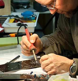 Man working on circuit board with soldering iron - photo by Blaz Erzetic from Pexels