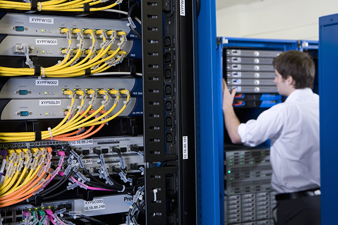 Tech in server room with networking equipment