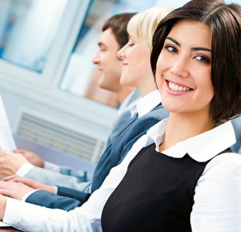 People in meeting, woman smiling at viewer in the foreground