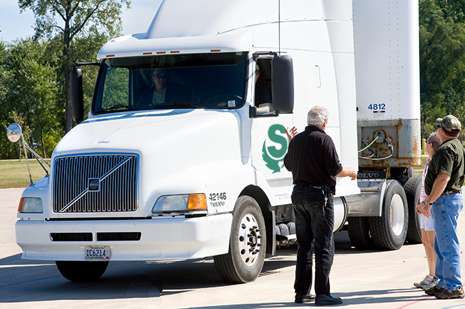 Instructor talking with students near a truck in a parking lot