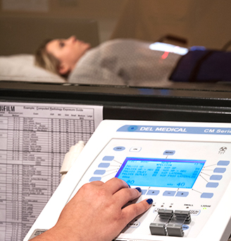 Radiology tech's hand on a control with paitent in the background