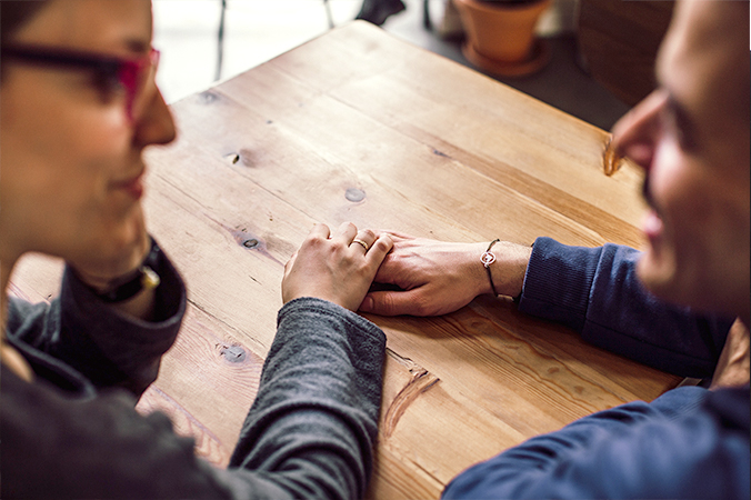 Two people touching hands at a table - photo by Juan Pablo Serrano Arenas from Pexels