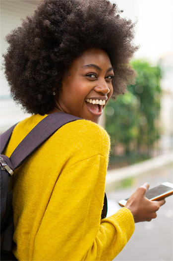 College Student walking and smiling and laughing over her shoulder